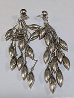 Front view of one sterling silver dangle earring showing multiple elongated leaf-shaped charms hanging from chains attached to a stud post.