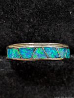 Close-up of the ring's opalite inlay on sterling silver band against black fabric background.