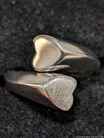 Close-up image of sterling silver ring showing two heart-shaped ends, one with a polished surface and the other with a matte texture.