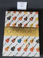Front cover of the hardcover book 'Acoustic Guitars: The Illustrated Encyclopedia' showing colorful guitar illustrations and gold title band.
