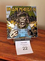 Iron Maiden 6x6 carnival mirror front view with sharp graphic of monstrous figure with cannons firing.