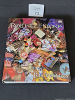 Photo of the large hardcover book 'Rolling With The Stones' by Bill Wyman showing colorful cover art with memorabilia images.
