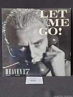Front cover of Heaven 17 'Let Me Go' 12 inch vinyl single showing close-up of a man's face holding a telephone receiver with the title text.