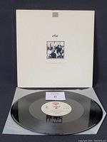 Front cover of a-ha "Hunting High and Low" vinyl record album with white sleeve and centered band photo and title.