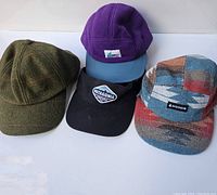 Lot of 4 hats: green tweed, purple fleece (MEC), black Patagonia visor, patterned multi-color Woods cap