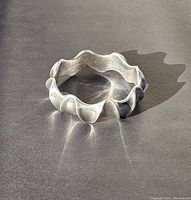 Bangle resting on black surface, full front view