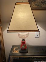 Full view of the antique table lamp with shade on, placed on a decorative black table.