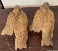 Top view of two metal bird figurines showing detailed feather engraving and spread wings