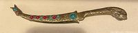 Front view of the brass letter opener showing textured design with red and turquoise stones embedded on handle and sheath.