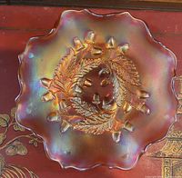 Top view of iridescent carnival glass plate showing embossed acorn and leaf design and scalloped edges.