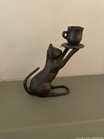 Side angle showing the cat figure reaching upward with tail curved behind