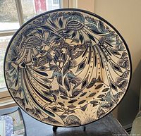 Front view of the large round decorative plate featuring intricate blue and white designs depicting stylized animals and floral motifs.