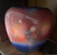 Front view of a large rounded pottery vase with glossy finish and gradient color from blue base to reddish top, showing glaze detail.