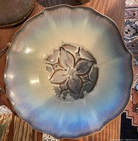 Top-down image of pottery bowl showing scalloped edges and central floral motif.