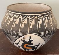 Front top angle showing intricate geometric designs and the stylized animal figure on the pottery jar.