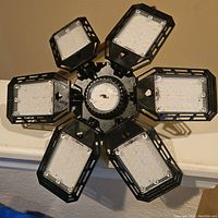 Top view of the black LED garage light showing six rectangular LED panels with clear plastic covers arranged radially around the central base.
