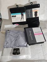 Four packages of new women's clothing items including leggings and lounge shorts on hangers and in sealed packages.