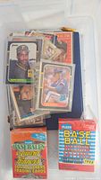 Plastic container with loose and sleeved vintage baseball cards including a boxed Fleer Base Ball Record Setters 1988 set.