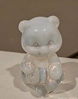 Front view of the small opalescent glass bear figurine showing smooth shiny surface and details in face and paws