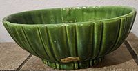 Side view showing vertical ridges and Haeger label on green glazed ceramic oval planter dish