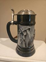 Side view showing the detailed grayscale character artwork on the ceramic stein with metal pewter lid attached.