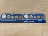 Two United States Special Mint Sets from 1966 and 1967 displayed side by side in plexiglass cases with original blue sleeves.