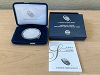 2017 American Eagle silver proof coin in a velvet presentation box with original outer box and certificate booklet visible on a table.