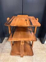 Front view of 3 tiered wooden accent table showing the three shelves and decorative supports