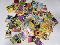 Image showing a large scattered pile of Pokemon trading cards on a white background highlighting various characters and energy types.