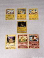 Group of 6 Pokémon trading cards spread on white background, featuring five Pikachu cards and one Charmander card.