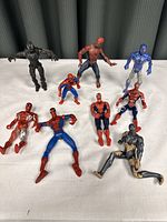 Top full view of ten Spiderman-related action figures arranged upright or sitting, showing different variants and sizes