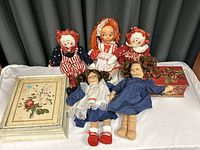 Group photo of five vintage dolls and two boxes on a white cloth