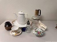Group shot showing all items including teapot, coffee carafe, lidded dish, cup and saucer, salt shaker, small pot, gravy boat, and small blue bowl