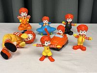 Group of 7 different Ronald McDonald figures, various sizes and poses on table