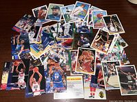 Photo showing a spread of around thirty assorted sports cards mostly basketball players with a few baseball cards.
