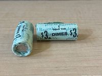 Two blue paper rolls, one intact and one partly unrolled, printed “Harrah’s $3 DIMES” with tear tab.