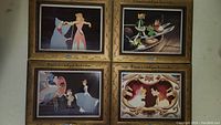 Four framed Disney Cinderella art prints with gold-colored, ornate frames and decorative borders showing different scenes from the movie.