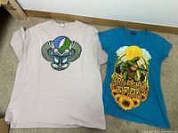 Two Grateful Dead t-shirts laid flat on floor showing front graphics.