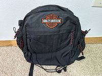 Front view of the black Harley Davidson bag with logo and elastic cord on the front pocket.