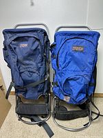 Two Jansport backpacks side by side showing full front view and metal frame support