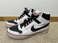 Side view of the pair of Nike Delta Force sneakers showing black and white leather with red accents, black laces, and used condition.