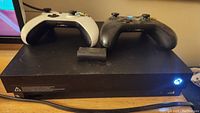 Xbox One X console front view with two controllers on top
