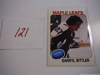 Front side of 1975-76 O-Pee-Chee Darryl Sittler hockey card showing player in action pose in Maple Leafs uniform.