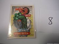 Clear photo of Garbage Pail Kids Dire Rita sticker showing full artwork and card number 389a.