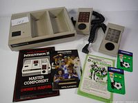 Vintage beige Intellivision II system console with two controllers, manuals, and soccer game inserts displayed.