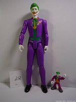 Full view of the large Joker action figure standing next to the smaller mini-figure, both with purple outfits and green hair.
