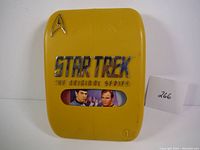 Front view of yellow plastic case with chrome Star Trek emblem and series title.