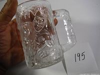 Photo showing embossed robin bird design and textured surface of the glass mug held in hand.