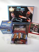 Boxed Star Trek model kit featuring The Enterprise and character heads, two ceramic mugs in boxes, Star Trek: TNG Reunion novel, and a collectible figurine in box.
