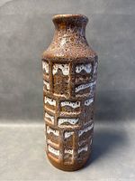 Front view of the pottery vase showing brown textured body with white geometric rectangular patterns.